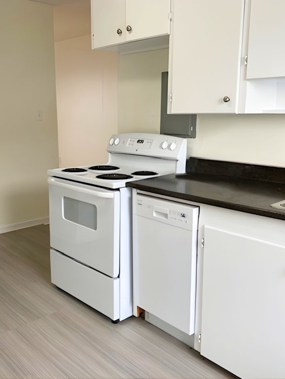 A modern kitchen with a stainless steel refrigerator and wooden flooring.