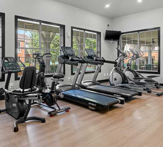 A spacious gym with a variety of exercise equipment and a television.