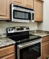 A kitchen with a black stove top oven and microwave above it.