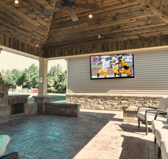 a covered patio with a fireplace and tv