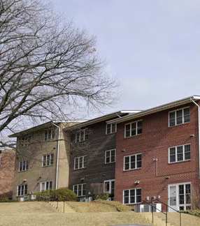 A car is parked in front of a brick apartment building.at Normandy Hill Apartments, Virginia