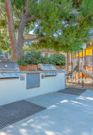 a bbq area with two grills and a playground in a yard at Citrus Court Apartments, Whittier, CA, 90606