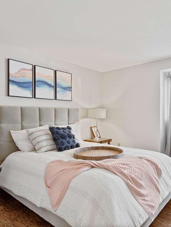 A bedroom with a large bed and a window overlooking a tree-filled yard at MonteVista Apartments, Beaverton, 97007
