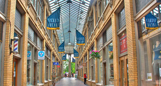 a city street with shops and a glass ceiling