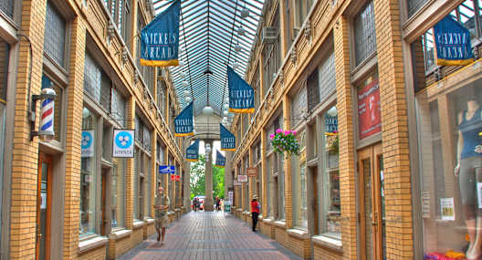 a city street with shops and a glass ceiling