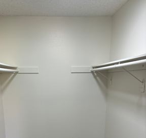 A white wall with a metal shelf and a poster on the wall.