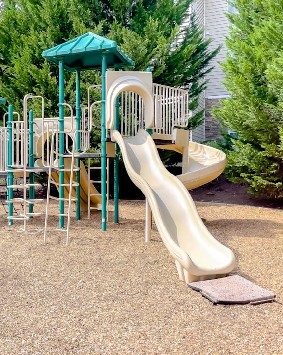 A playground with a green roof and a yellow slide.