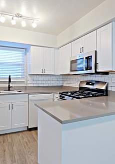 A kitchen with white cabinets and a stainless steel refrigerator.