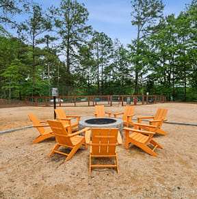 a fire pit with chairs around it in a park