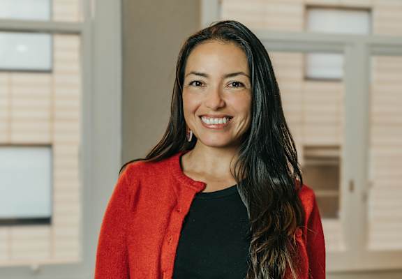 a woman in a red jacket and black shirt is smiling at the camera