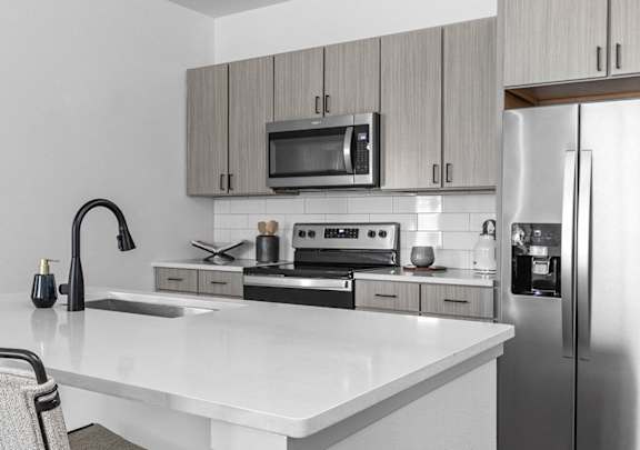 A kitchen with a white countertop and a stainless steel refrigerator.