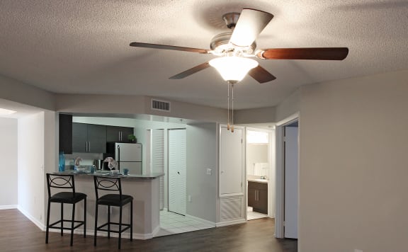 Empty living room with a kitchen in the background and ceiling fan at Pembroke Pines Landings, Florida, 33025