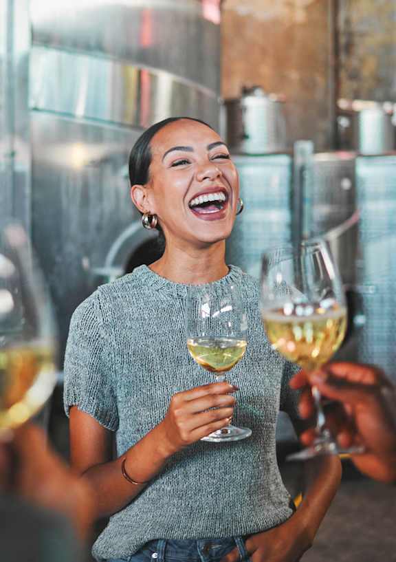 A group of people are laughing and toasting with glasses of white wine.at The William, Chantilly, VA 20152