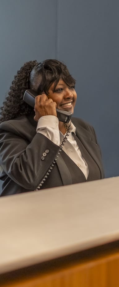 a woman sitting at a desk talking on a cell phone