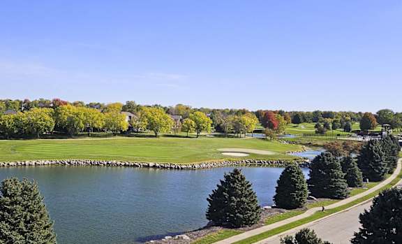 a view of a golf course and a pond surrounded by trees