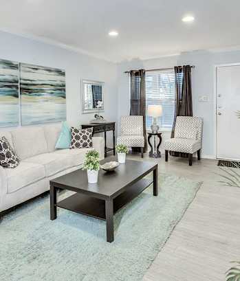 A living room with a white couch, a coffee table, and a painting on the wall.
