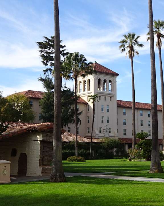 A building with a tower and palm trees in front of it.