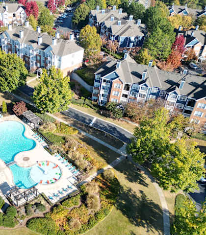 An aerial view of a residential area with a swimming pool and apartment buildings. at The Crest at Sugarloaf, Lawrenceville, GA