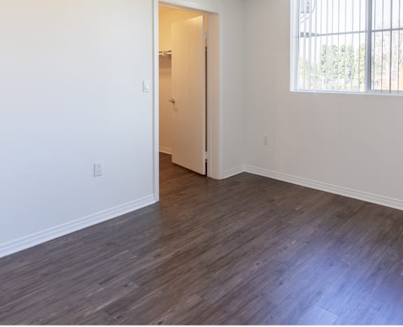 an empty bedroom with white walls and wood floors