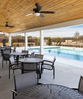 a patio with tables and chairs next to a pool