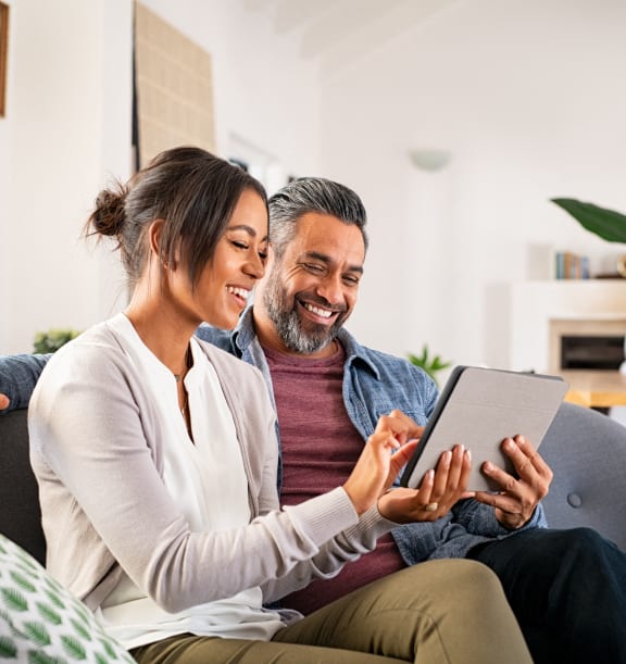 a couple sitting on a couch looking at a tablet computer