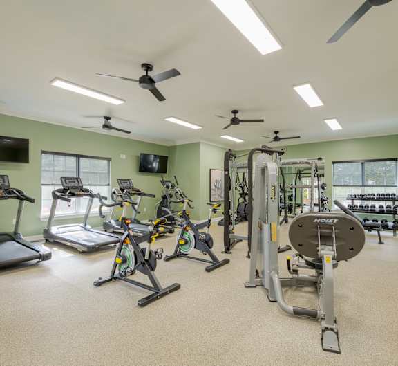 A spacious gym with a variety of exercise equipment including treadmills, stationary bikes, and weight machines.