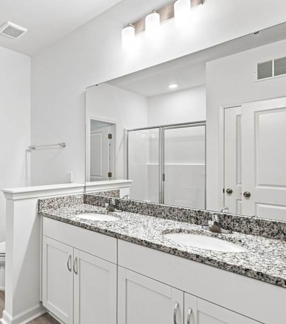 A bathroom with a marble countertop and white cabinets.