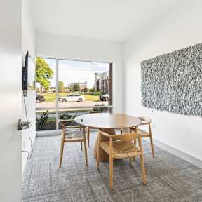 A room with a table and chairs and a painting on the wall.