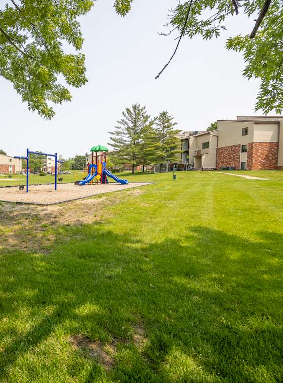 A playground with a slide and a green lawn. at Indian Ridge Apartments, Davenport, Iowa