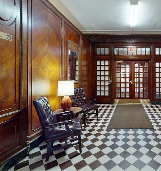 A hallway with a checkered floor and wooden doors.