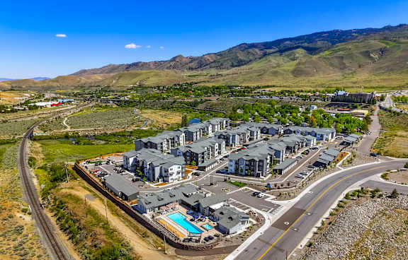 A large building complex with a swimming pool in the foreground and a winding road in the background.