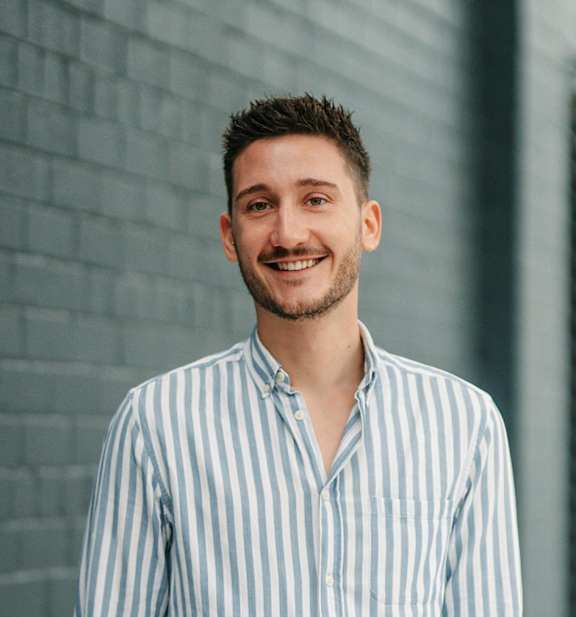 A man with a beard and short hair is wearing a striped shirt.
