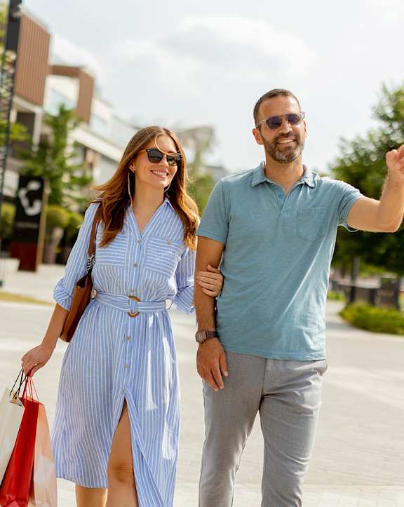 A man and woman are walking together, the man is pointing to something.