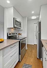 A kitchen with white cabinets and a black refrigerator.