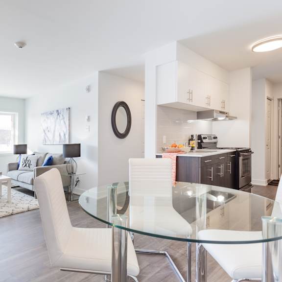 A modern living room with a glass table and white chairs.