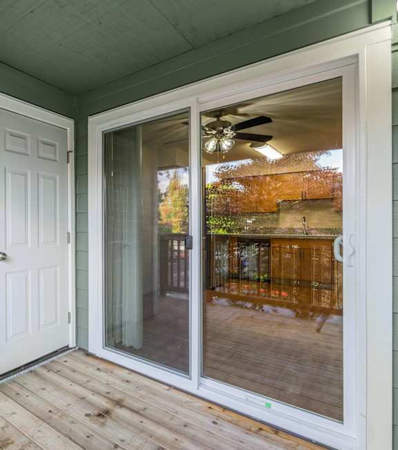 A white door and sliding glass window on a porch.