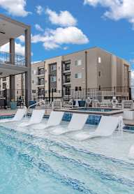 A modern building with a pool and lounge chairs.