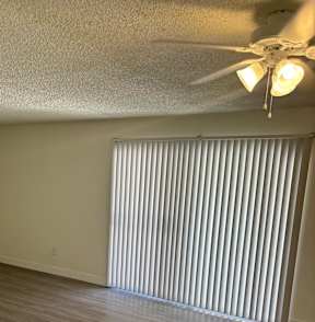 A ceiling fan with lights is mounted on a wall above a window with blinds.