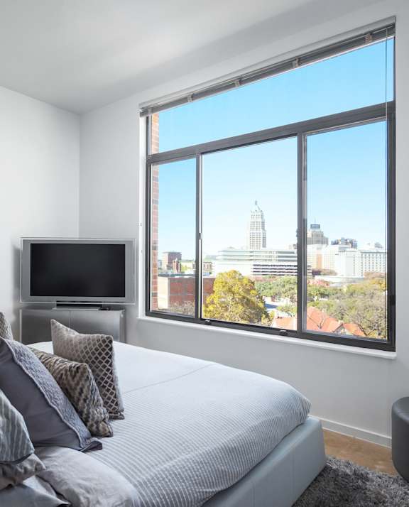 A bedroom with a bed, dresser, and window.