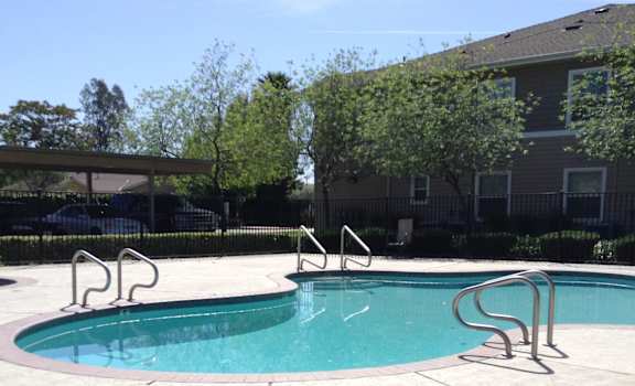 Image of swimming pool with parking and building in the background