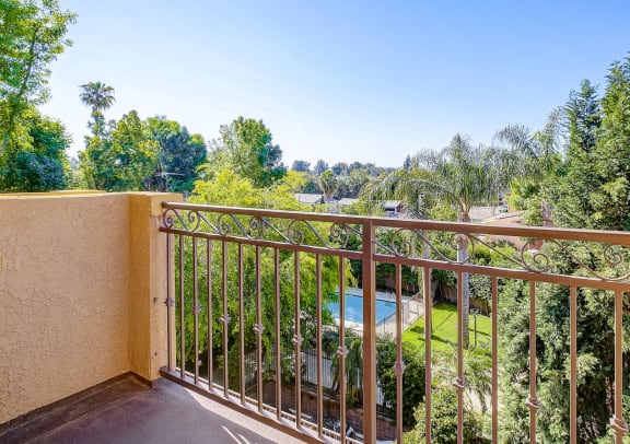 a balcony with a view of a pool and trees