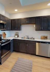 A modern kitchen with dark brown cabinets and stainless steel appliances.