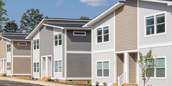 Richmond model townhomes at Belle Meadow in Asheville with varied siding and white trim under a partly cloudy sky.