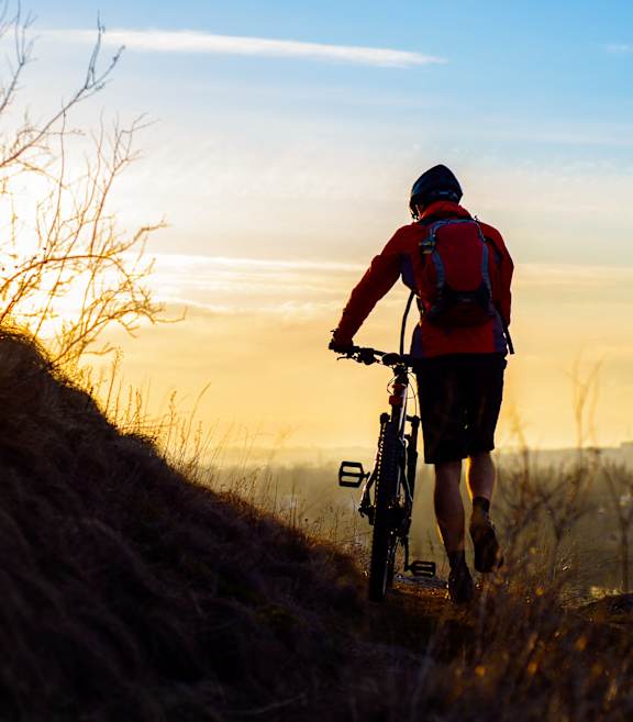 A person riding a bike on a trail during sunset.