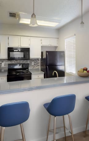 a kitchen with a bar and three stools in front of a quartz counter top