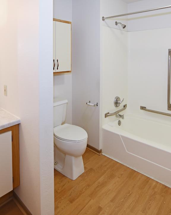 A white bathroom with a toilet, sink, and bathtub. at Aspen Apartments, Hudson