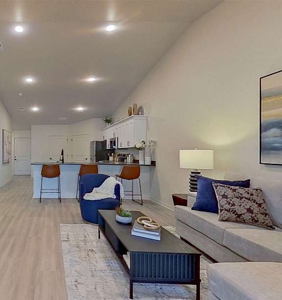A spacious living room with a logo of Lombardo Apartments on the wall.