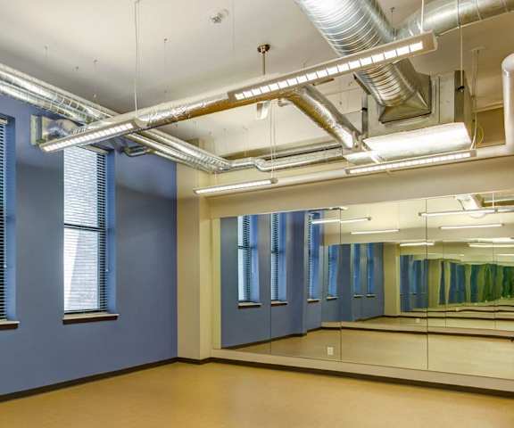A room with wooden floors and a row of windows.