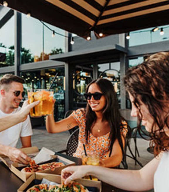 people sitting at a table eating food and drinking beer