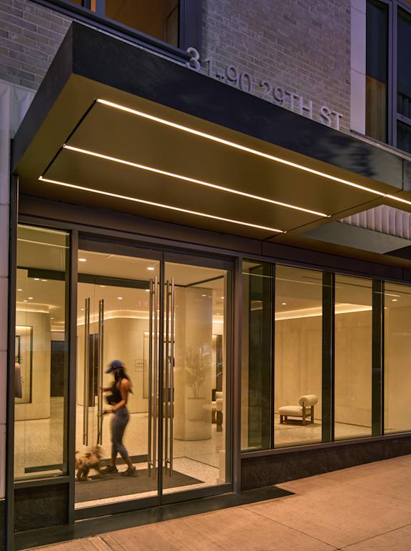 A woman is walking out of a building with a glass door.